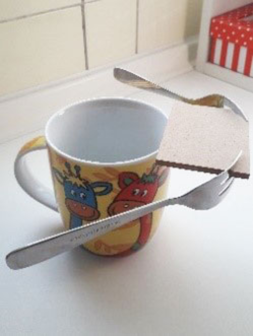 Das Bild zeigt einen bunten Becher mit Tiermotiven, in dem eine Gabel und ein Messer sowie ein St&uuml;ck Holz platziert sind. Diese Anordnung k&ouml;nnte f&uuml;r ein Experiment zur Schwebetechnik oder zum Thema Auftrieb verwendet werden.