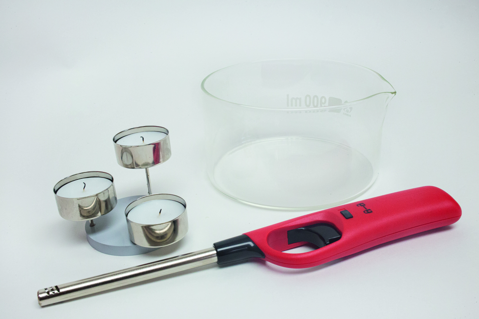 Das Bild zeigt ein breites Glas, drei Teelichter in einer Halterung und ein Feuerzeug. Diese Gegenst&auml;nde sind typisches Experimentiermaterial f&uuml;r den Unterricht in Naturwissenschaften.