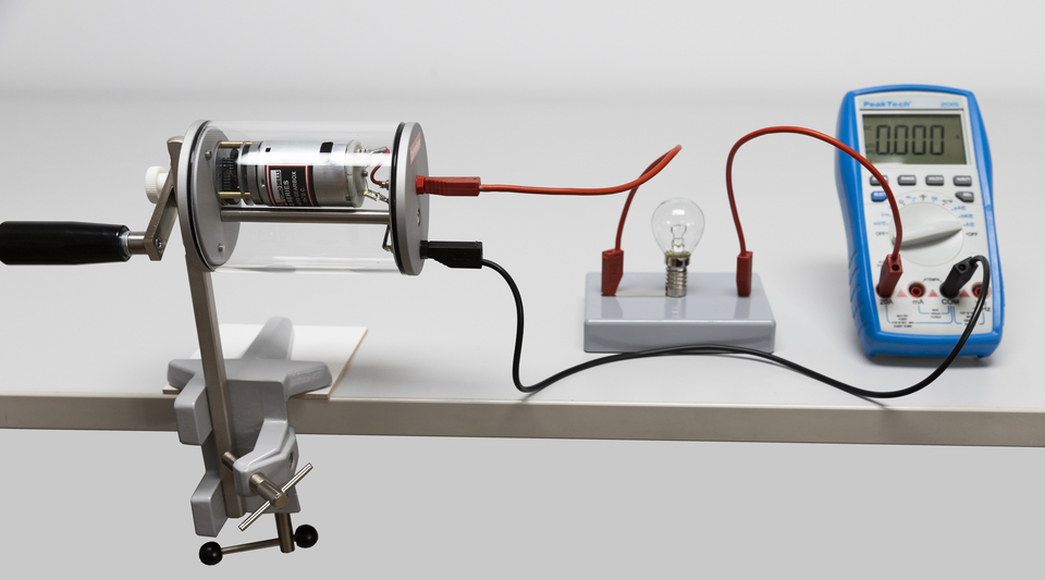 Das Bild zeigt ein Experimentierger&auml;t, den Dynamot von Cornelsen Experimenta, mit einem Motor, der mit einer Gl&uuml;hbirne und einem Multimeter verbunden ist. Die Anordnung dient zur Veranschaulichung elektrischer Stromkreise und der Messung von Stromst&auml;rke.