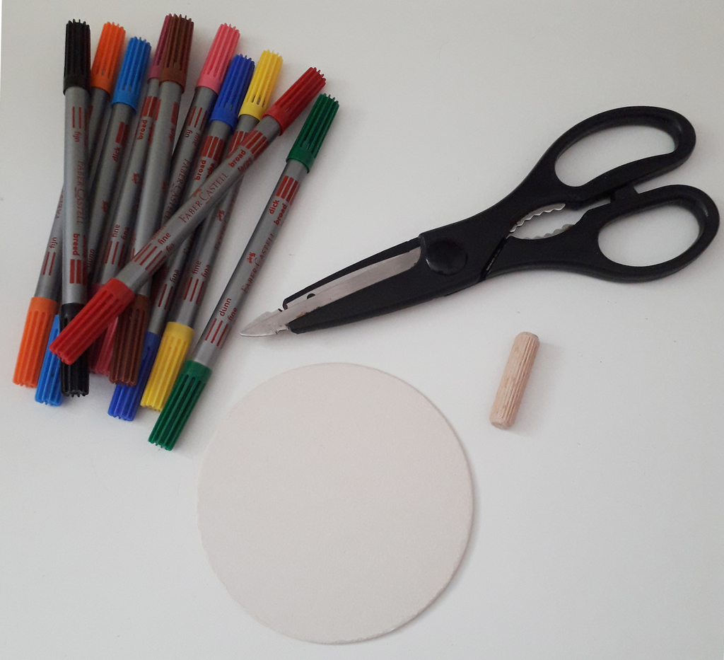 Auf der Arbeitsfläche liegen bunte Filzstifte, eine Schere, ein Holzstab und eine runde, helle Fläche. Diese Materialien eignen sich für vielfältige kreative Experimente und Bastelprojekte im Bildungsbereich.