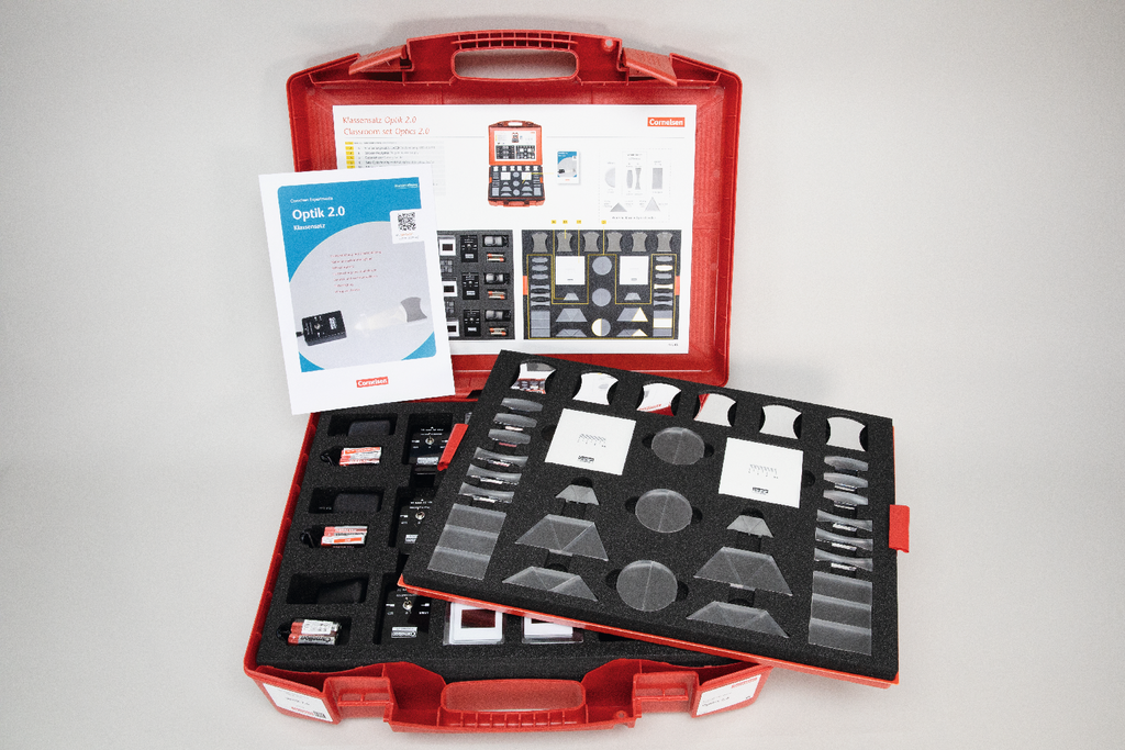 Das Bild zeigt einen roten Koffer mit einem Experimentierset f&uuml;r den Bereich Optik, das aus verschiedenen Linsen und optischen Elementen besteht. Dazu geh&ouml;rt auch ein Begleitheft, das Anweisungen und Informationen zu den enthaltenen Materialien bietet.