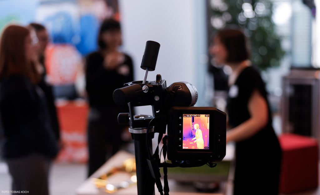 Girls Day 2024 im Bundeskanzleramt: im Vordergrund zeigt eine W&auml;rmebildkamera das Bild einer weiblichen Person, im Hintergrund sind mehrere Personen verschwommen zu sehen.