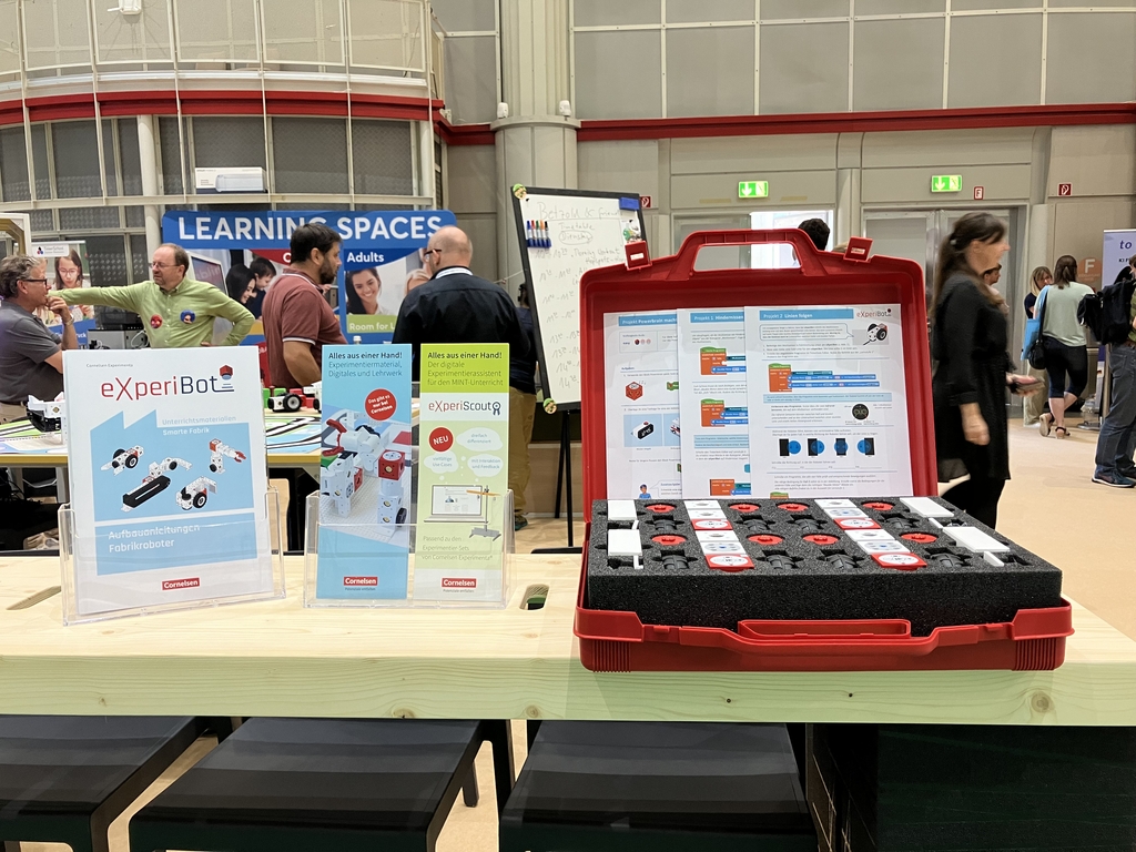 Mobile Schule Tagung 2024, im Vordergrund ist ein offener eXperiBot Koffer zu sehen, im Hintergrund sind Menschen.
