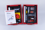 Das Bild zeigt ein Experimentier-Set für Schüler mit dem Titel "Mechanik 1", das in einem roten Kasten untergebracht ist. Es enthält verschiedene Materialien und Werkzeuge, die für praktische Experimente im Bereich Mechanik verwendet werden können.