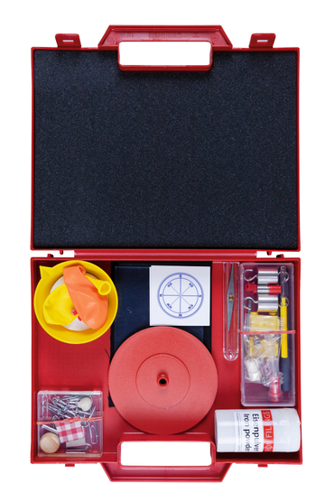 Das Bild zeigt eine rote Experimentierbox, die eine Vielzahl von Materialien für wissenschaftliche Experimente enthält, darunter Ballons, einen Kompass, Eisenpulver und verschiedene Werkzeuge. Die Box ist übersichtlich angeordnet und eignet sich ideal für
