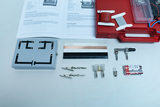 Das Bild zeigt eine Auswahl an Experimentiermaterialien, darunter eine Schaltungseinheit, Kabel, verschiedene Metallstreifen und Batterien, die für physikalische Experimente verwendet werden können. Auch Anleitungen zur Durchführung von Versuchen sind ent