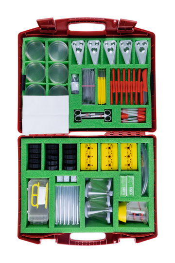Das Bild zeigt einen umfangreichen Experimentierkasten, der verschiedene Utensilien wie Reagenzgläser, Petrischalen, Messgeräte und Pipetten enthält. Alle Teile sind ordentlich in einem roten Koffer mit grünem Schaumstoffpolster angeordnet, was die Organi