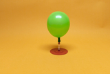 Das Bild zeigt einen grünen Ballon, der auf einer rotfarbenen Basis angebracht ist. Der Ballon scheint durch ein Schlauchsystem verbunden zu sein, das für Experimente im Bildungsbereich genutzt werden kann.