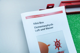Das Bild zeigt den Umschlag einer Mini-Box aus dem Bereich Elementarphysik, die sich mit den Themen Luft und Wasser beschäftigt. Die Box gehört zu den Experimentiermaterialien von Cornelsen und scheint für den Einsatz im Bildungsbereich konzipiert zu sein