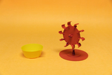Das Bild zeigt ein rot gefärbtes Wasserrad auf einem Standfuß und eine gelbe Schale daneben. Diese Objekte dienen wahrscheinlich als Lehrmaterial für Experimente im Bereich der Physik oder Ingenieurwissenschaften.