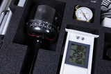 Das Bild zeigt eine Werkzeug- oder Experimentierbox mit verschiedenen Messtechnikgeräten, darunter ein Thermometer und ein Kompass. Die Geräte sind in passgenauer Schaumstoffeinlage angeordnet, um die Sicherheit und Ordnung beim Transport zu gewährleisten