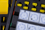 Das Bild zeigt ein Experimentier-Set mit mehreren Kompassen in transparenten Boxen sowie gelben Halterungen und einem Stift. Die gesamte Ausstattung ist in einer schwarz-schaumstoffeingelegten Box organisiert, die für den Einsatz im Bildungsbereich konzip