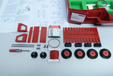 Das Bild zeigt ein Experimentierkit für das deutsche Bildungswesen, das verschiedene rote Bauteile, darunter Schaltkreise und Räder, sowie ein Handbuch zur Anleitung enthält. Die Komponenten sind in einer roten Box angeordnet und bieten die Möglichkeit, e