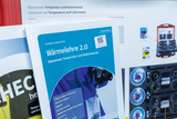 Das Bild zeigt Materialien aus einem Online-Shop für Experimentierbedarf, darunter Anleitungen zu Temperatur und Kalorimetrie. Im Vordergrund befindet sich ein Handbuch mit dem Titel „Wärmelehre 2.0“, das sich mit den Grundlagen thermischer Experimente be