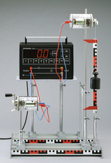 Das Bild zeigt ein Experimentiergerät zur Energie- und Leistungsanalyse, bestehend aus einem digitalen Messgerät und zwei Motoren, die mit Kabeln verbunden sind. Ein schwerer Block ist ebenfalls integriert, um die mechanischen Eigenschaften in den Experim
