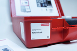 Das Bild zeigt einen roten Aufbewahrungskasten mit dem Etikett „Cornelsen Experimenta Demo-Set Fotovoltaik“. Im Hintergrund ist eine Informationsseite zu sehen, die vermutlich weitere Details zu den Inhalten und Anwendungen des Sets bietet.