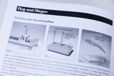 Das Bild zeigt Anweisungen zum Aufbau eines Experiments zum Thema Flug und Fliegen. Es sind schematische Darstellungen von Halterungen für ein Kraftmesser, Widerstandskörper und die Montagepunkte des Versuchsaufbaus abgebildet.