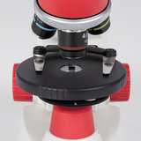 Das Bild zeigt ein Mikroskop, das mit einem roten und schwarzen Design ausgestattet ist. Die Objektivträgerplatte ist gut sichtbar, und es sind verschiedene Objektive mit unterschiedlichen Vergrößerungen zu erkennen, die für die mikroskopische Untersuchung verwendet werden können.