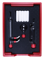 Das Bild zeigt ein Set von Laborgeräten, das in einer roten Kunststoffbox mit Schaumstoffeinlage präsentiert wird. Enthalten sind verschiedenen Glaswaren, darunter Reagenzgläser und eine Kugel, die für Experimentierzwecke im Bildungswesen gedacht sind.