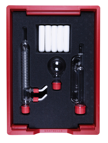 Das Bild zeigt ein Set von Laborgeräten, das in einer roten Kunststoffbox mit Schaumstoffeinlage präsentiert wird. Enthalten sind verschiedenen Glaswaren, darunter Reagenzgläser und eine Kugel, die für Experimentierzwecke im Bildungswesen gedacht sind.