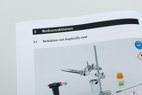 Das Bild zeigt eine Anleitung zu einer Redoxreaktion, speziell zur Reduktion von Kupfer(II)-oxid. Es sind verschiedene Laborgeräte und Chemikalien abgebildet, die für das Experiment benötigt werden.