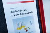 Das Bild zeigt ein Schüler-Set mit dem Titel "Mein Körper, meine Gesundheit". Es enthält verschiedene Utensilien wie Reagenzgläser und Proben, die für Experimente zur Untersuchung des menschlichen Körpers und der Gesundheit verwendet werden können.