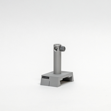 Das Bild zeigt einen grauen Stativhalter aus Metall, der für Experimente im Bildungsbereich verwendet wird. Der Halter hat einen stabilen Standfuß und eine aufrechte Stange mit einer seitlichen Schraube zur Befestigung von Zubehör.