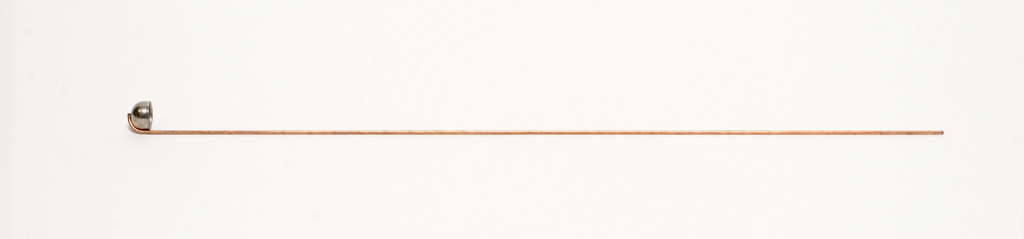 Das Bild zeigt einen langen, dünnen Kupferdraht mit einer gebogenen Metallspitze an einem Ende. Dieser Draht könnte für chemische Experimente oder physikalische Demonstrationen verwendet werden.