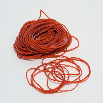 Das Bild zeigt eine Menge roter Gummischnüre, die in einem lockeren Knäuel angeordnet sind. Eine kleinere Partie von Gummischnüren liegt daneben und hat eine wellenförmige Struktur.