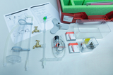 Das Bild zeigt ein Set für Experimente im Bereich Wassertechnik, bestehend aus verschiedenen Rohren, Wasserhähnen, elektrischen Komponenten und einem Handbuch zur Anleitung. Alle Teile sind ordentlich angeordnet und in einem roten Behälter mit Schaumstoffeinlage verpackt.