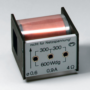 Das Bild zeigt einen Transformator für experimentelle Anwendungen im Bildungsbereich. Er hat eine Kupferspule und verschiedene Anschlussbuchsen, mit Angaben zur Leistung und Spannung auf der Vorderseite.