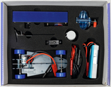 Das Bild zeigt ein Experimentier-Kit zur Konstruktion und Nutzung eines kleinen Fahrzeugs. Es enthält verschiedene Komponenten wie ein Fahrzeugchassis, einen Motor, Kabel und eine Energiequelle, alles ordentlich in einem Schaumstoffeinsatz verpackt.