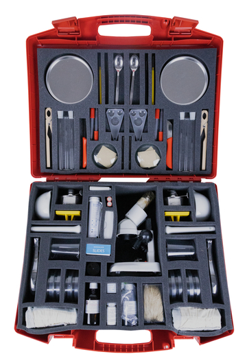 Das Bild zeigt eine rote Werkzeugkiste, die mit verschiedenen Experimentiermaterialien und -geräten ausgestattet ist. Sie enthält unter anderem Gläser, Mikroskopzubehör, Pipetten und andere Schulsachen für naturwissenschaftliche Experimente.