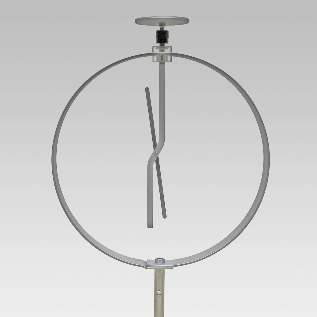 Das Bild zeigt ein Experimentiergerät, das aus einem runden Rahmen mit einer senkrechten Halterung und einem beweglichen, gebogenen Element besteht. Es wird vermutlich verwendet, um physikalische Prinzipien oder Bewegungen zu demonstrieren.