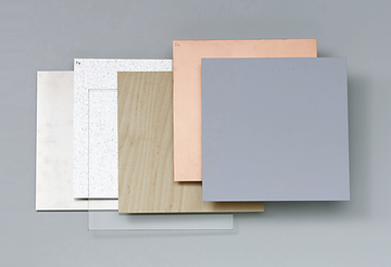 Das Bild zeigt eine Ansammlung von verschiedenen Materialien, darunter Holz, Metall und Kunststoff, die in quadratischen Plattenformaten angeordnet sind. Diese Platten sind wahrscheinlich für experimentelle Zwecke im Bildungswesen gedacht.