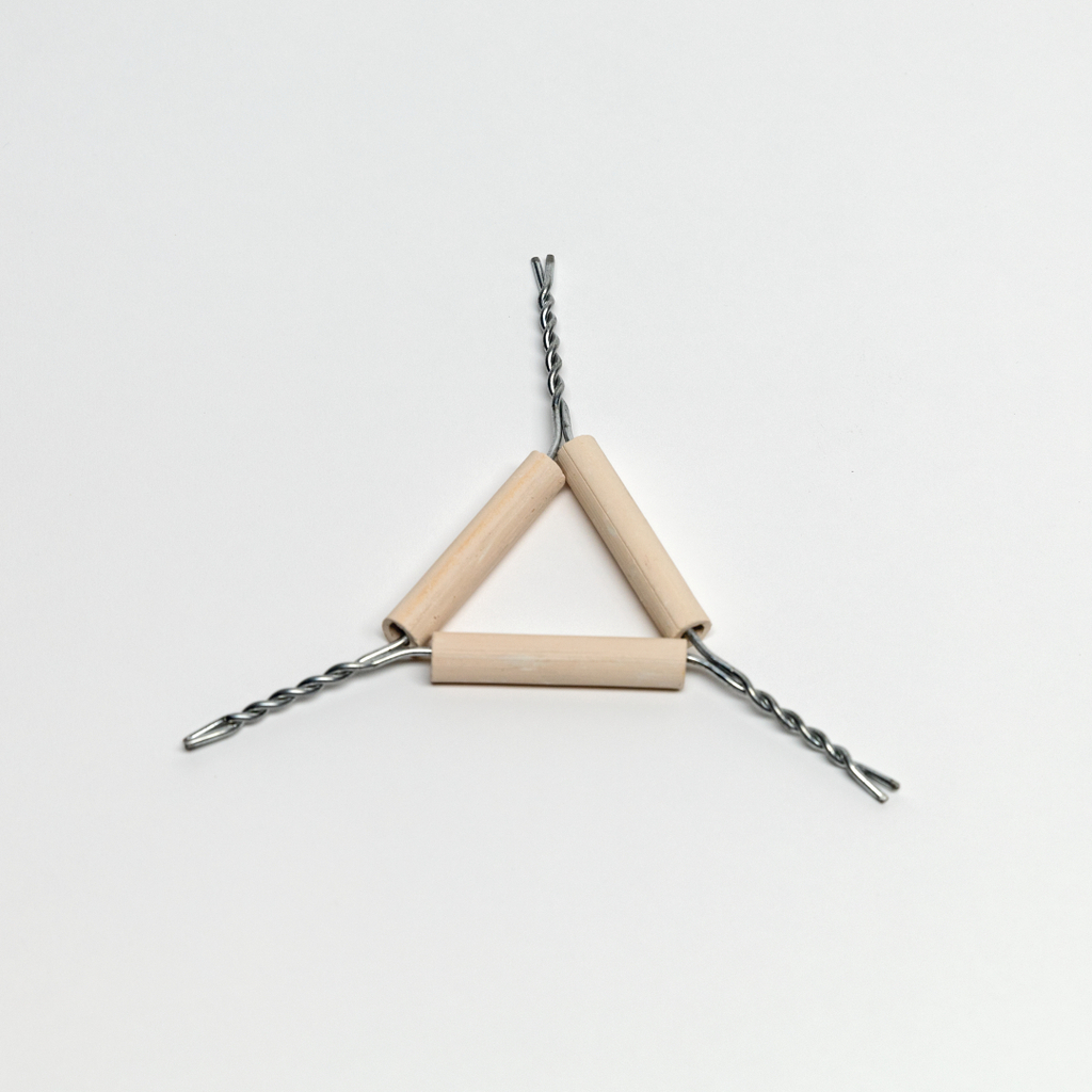 Auf dem Bild sind drei Holzrollen zu sehen, die durch spiralige Drahtverbindungen miteinander verbunden sind und eine dreieckige Form bilden. Der Hintergrund ist hell und unauffällig, wodurch der Fokus auf den experimentellen Aufbau liegt.