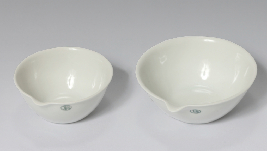 Das Bild zeigt zwei weiße Labor- oder Mischschalen aus Porzellan in unterschiedlichen Größen. Beide Schalen haben eine glatte Oberfläche und sind an der Kante leicht geschwungen, was sie für experimentelle Anwendungen geeignet macht.