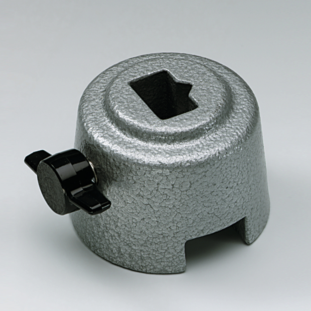 Das Bild zeigt einen stabilen Edelstahl-Brenner aus metallischem Material mit einer rauen Oberfläche, der eine Öffnung an der Oberseite besitzt. An der Seite befindet sich ein schwarzer Griff, der wahrscheinlich zur Regulierung der Flamme dient.