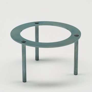 Das Bild zeigt einen stabilen Metallständer mit drei Beinen und einer runden, offenen Fläche in der Mitte. Er dient wahrscheinlich zur Unterstützung von Glaswaren oder anderen Experimentierutensilien in einem Labor oder Klassenzimmer.