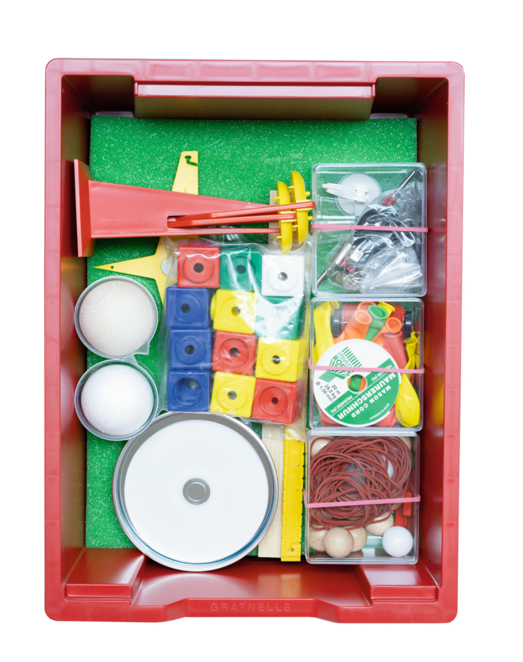 Das Bild zeigt eine rote Kiste mit verschiedenen Experimentiermaterialien für den Bildungsbereich. Darin befinden sich unter anderem Bälle, Bauklötze, Gummibänder und weitere Utensilien, die für physikalische oder kreative Experimente verwendet werden können.