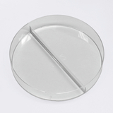Das Bild zeigt eine transparente Petrischale mit einer vertikalen Trennwand in der Mitte. Diese Schale wird häufig in wissenschaftlichen Experimenten verwendet, um Proben zu isolieren oder unterschiedliche Bedingungen zu schaffen.