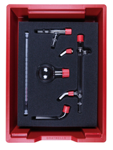 Das Bild zeigt ein Set von Glaslaborgeräten, das für Experimente im Bildungswesen konzipiert ist. Es umfasst eine Kugel, mehrere Rohre und einen Thermometer, alle sicher in einer roten Box mit Schaumstoffeinlage untergebracht.