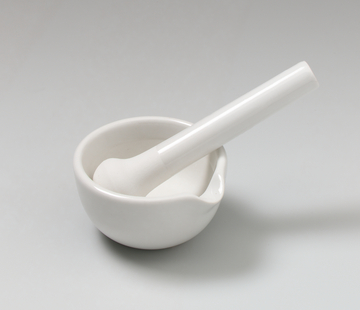 Das Bild zeigt ein weißes Porzellanmörser-Set, bestehend aus einer Schale mit einem passenden Stößel. Es wird häufig im Experimentierbedarf für chemische oder biologische Anwendungen verwendet.