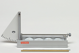 Das Bild zeigt ein Experimentiergerät zur Demonstration von physikalischen Prinzipien, bestehend aus einem Winkelmesser, einer Halterung für Kerzen und einem Schiebemechanismus. Unter dem Gerät liegen zwei Metallstangen, die möglicherweise zur Stabilisierung oder als weitere Experimentiermaterialien dienen.