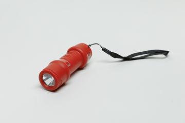 Das Bild zeigt eine rote Taschenlampe, die sich auf einem neutralen, hellen Hintergrund befindet. Sie hat eine Schlaufe und eine glatte Oberfläche, die für den Einsatz im Bildungsbereich oder bei Experimenten geeignet ist.