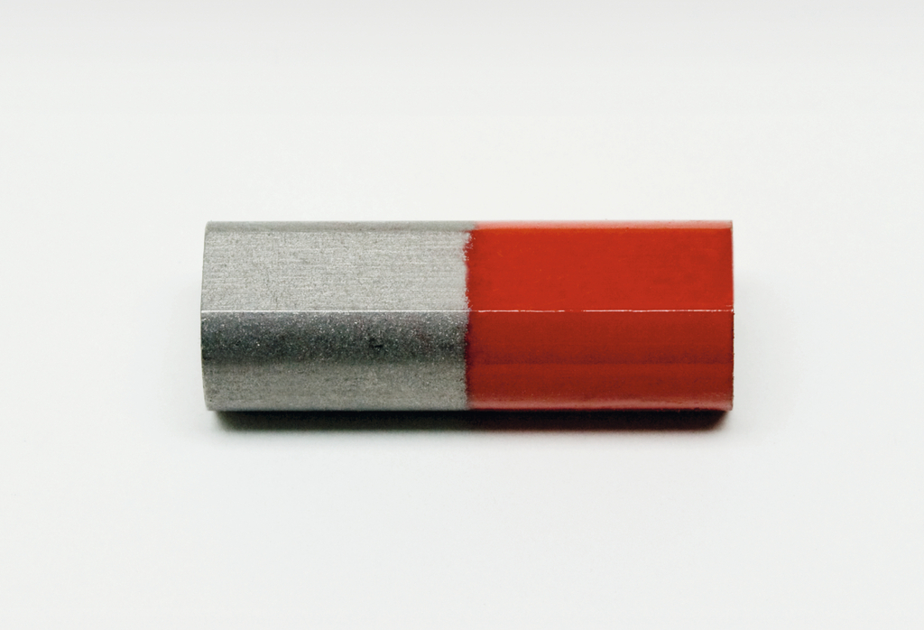 Das Bild zeigt einen zylindrischen Magneten, der halb silberfarben und halb rot ist. Der silberne Bereich repräsentiert den Nordpol, während der rote Bereich den Südpol darstellt, was typisch für magnetische Materialien ist.