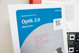Das Bild zeigt ein Handbuch zum Experimentiersatz „Optik 2.0“ von Cornelsen Experimenta, das verschiedene optische Phänomene behandelt. Es beinhaltet Themen wie Lichtausbreitung, Reflektion, Brechung und Farbzerlegung.