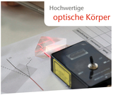 Das Bild zeigt eine hochwertige optische Linse in Form eines Prismas, durch das ein roter Laserstrahl projiziert wird. Daneben ist ein Experimentiergerät sowie ein Arbeitsblatt mit Diagrammen und Linien zur Untersuchung von Lichtbrechung und Reflexion zu sehen.