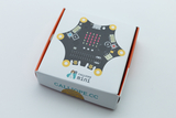 Das Bild zeigt eine Verpackung für das Calliope mini, ein Bildungsmodul für Experimente im Unterricht. Es ist flach und quadratisch, mit einer grafischen Darstellung des Moduls auf der Oberseite, die verschiedene Anschlüsse und Sensoren zeigt.