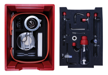 Das Bild zeigt einen roten Kasten mit Experimentiermaterialien, der verschiedene Laborgeräte und -utensilien enthält, darunter Glasröhren, Messbecher und eine Siphonpumpe. Alle Teile sind sicher in Schaumstoff eingepasst, um eine ordentliche Aufbewahrung zu gewährleisten.